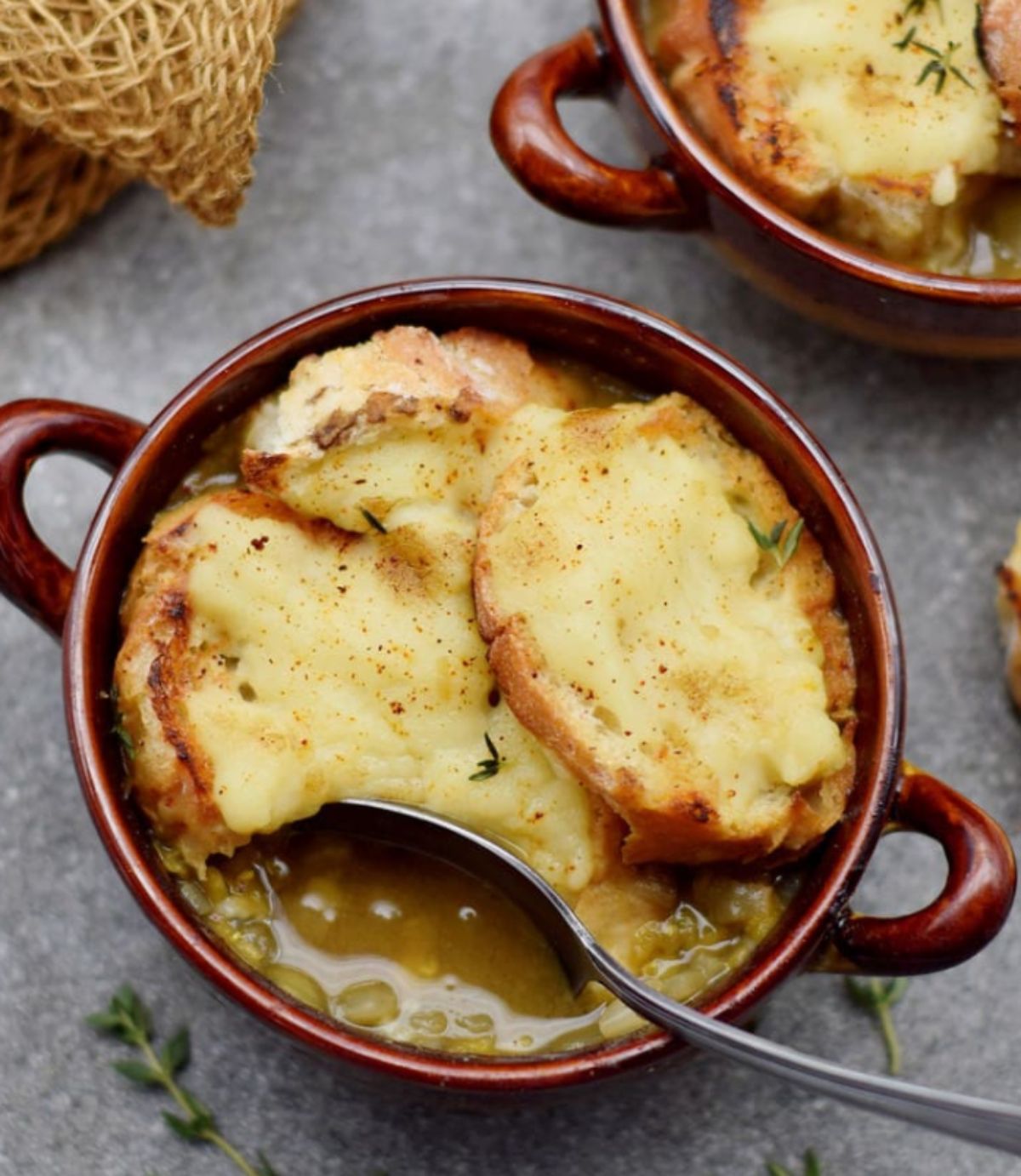 a small red casserole dish filled with french onion soup.