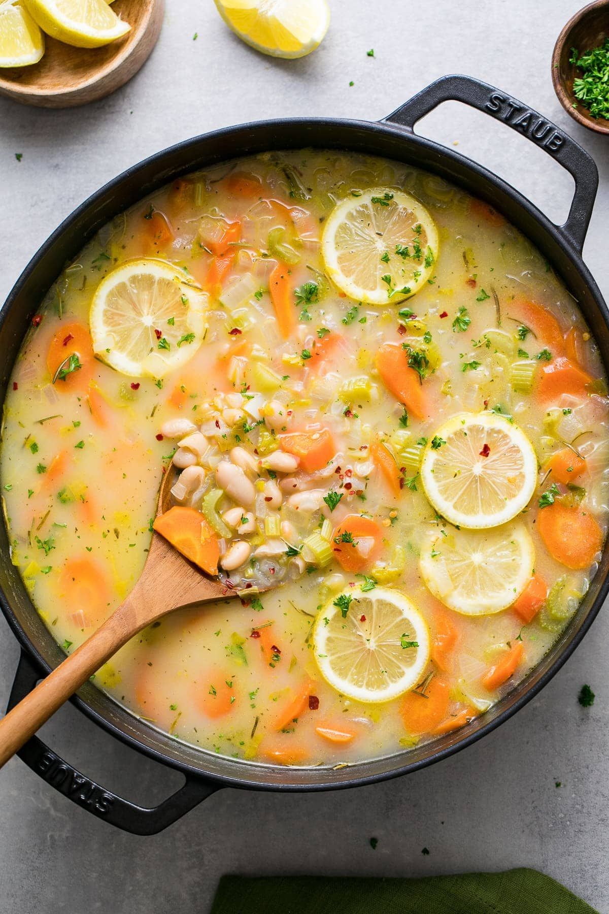 a cast iron pan full of white bean soup topped with sliced lemons