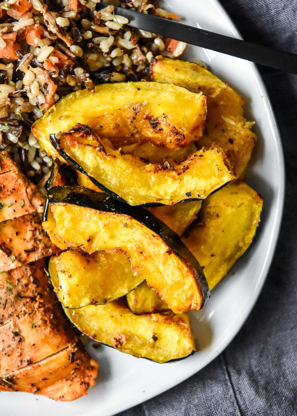 a partial view of a plate full of acorn squash slices next to a pile of grains