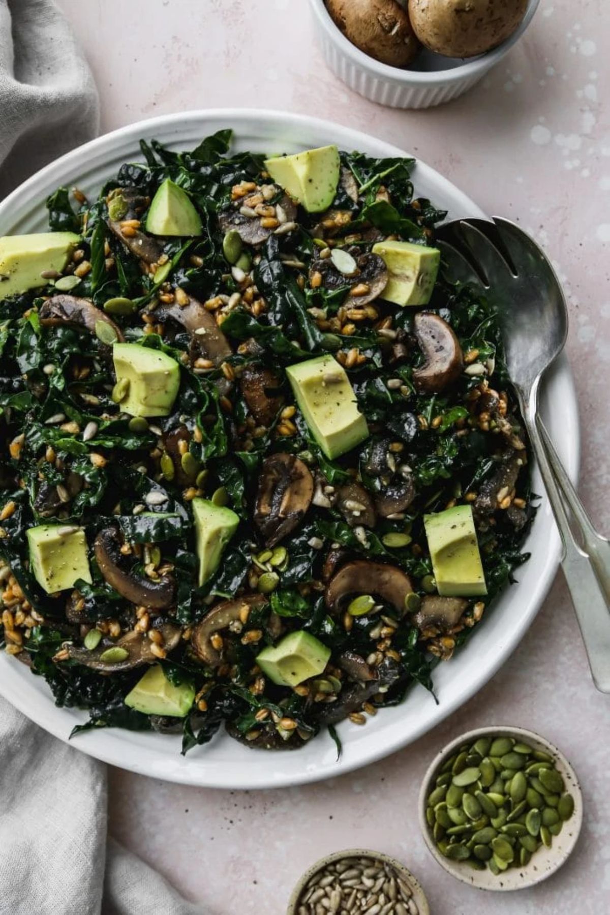 a plate of warm mushroom salad with miso dressing topped with avocado and pumpkin seeds