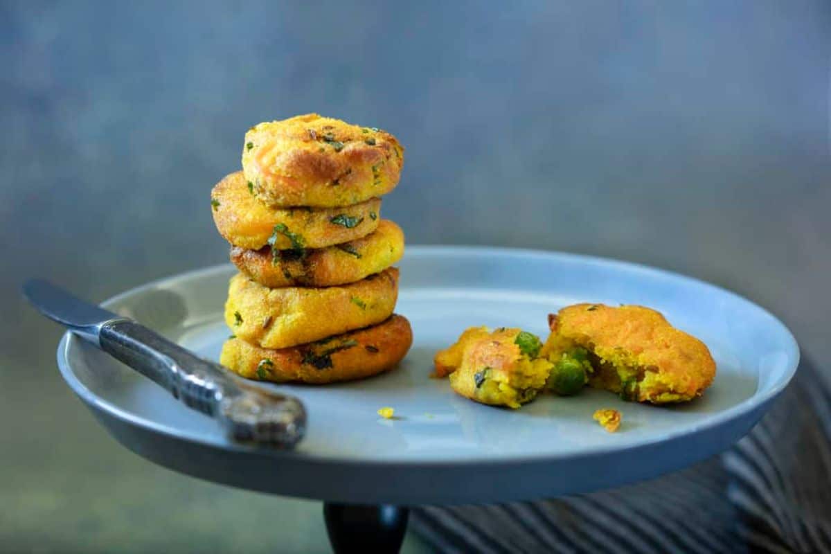 a blue plate holds a staack of potato patties, with one broken in half on the side and a knife resting on the other