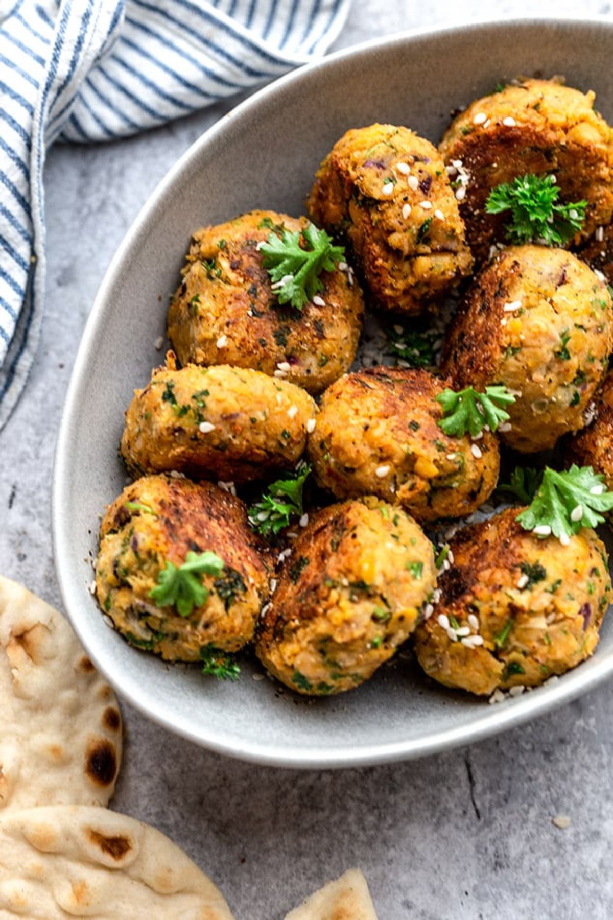 a dish full of falafels scattered with chopped parsley