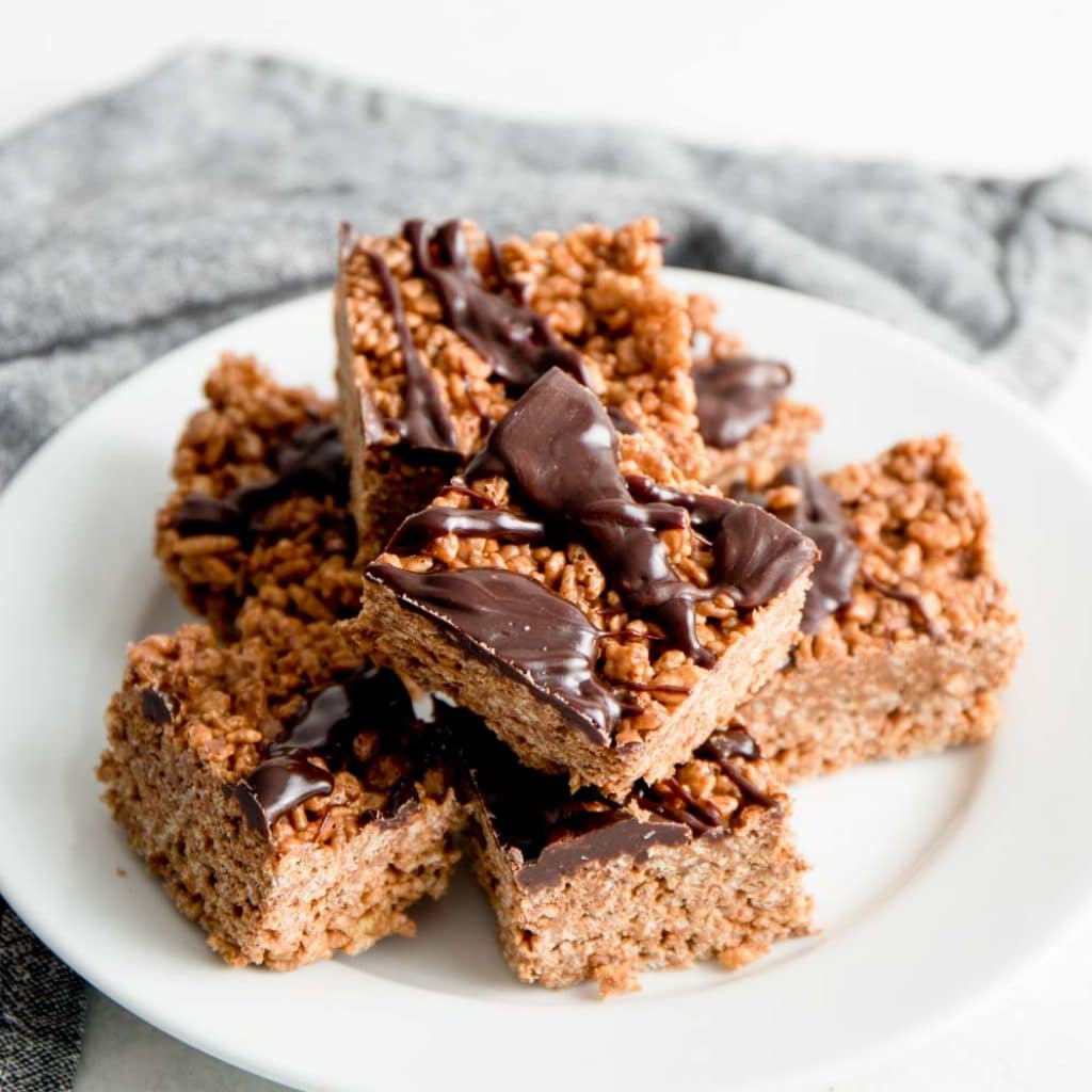 Peanut Butter Chocolate Rice Krispie Treats on a white plate with chocolate drizzle