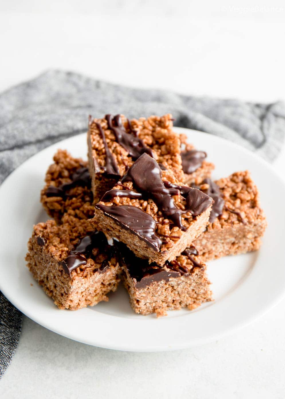 Peanut Butter Chocolate Rice Krispie Treats on a white plate with chocolate drizzle