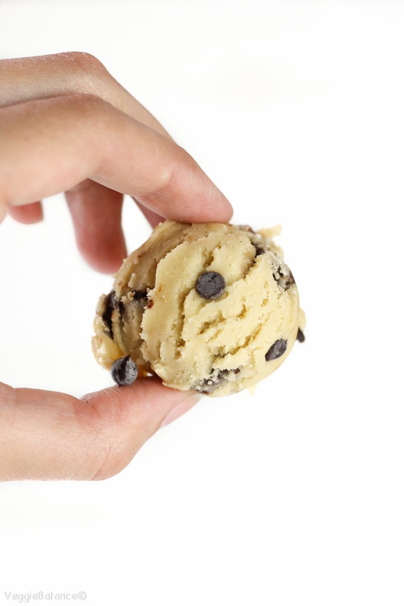 Edible Cookie Dough Ball being held with up to white background with hand