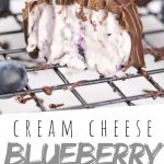 PINTEREST IMAGE with words "Cream Blueberry Cheese Truffles" Cream Blueberry Cheese Truffles on a cooling rack with one missing a bite