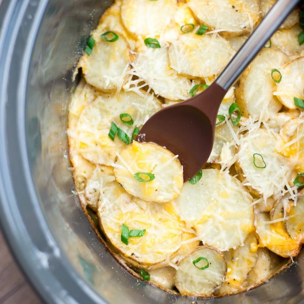 The Best Slow Cooker Scalopped Potatoes with cheese and green onion on top