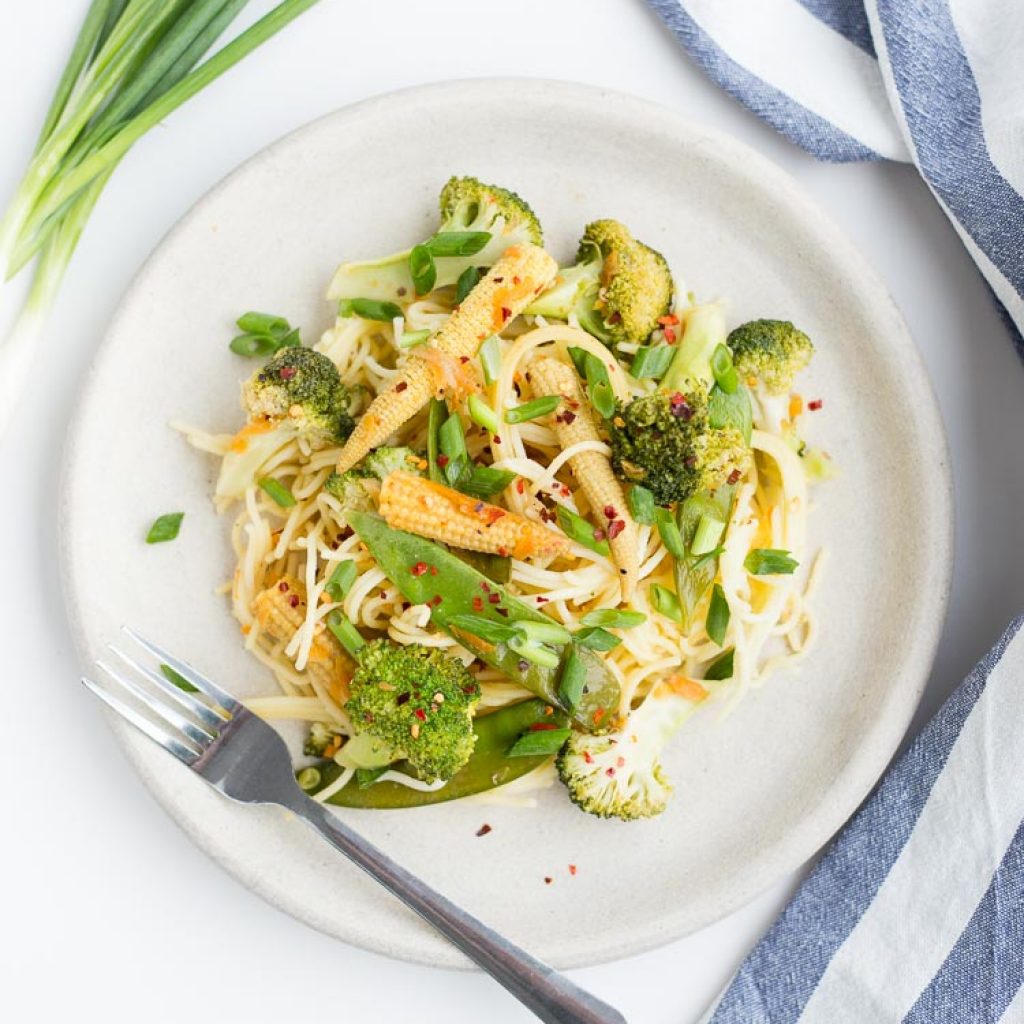 Overhead shot of Vegetarian Gluten Free Lo Mein with broccoli and corn on a plate with green onion on the side