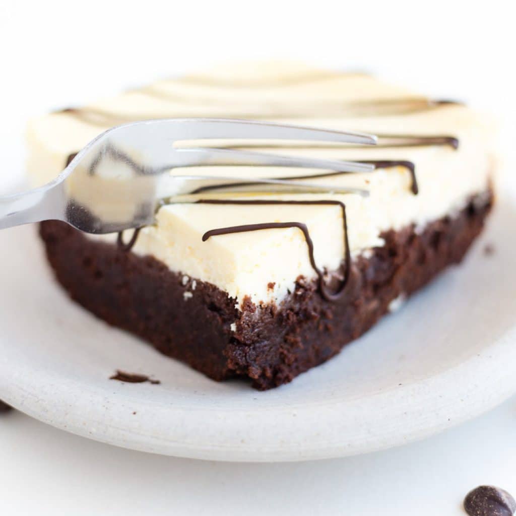 Gluten Free Cheesecake Topped Brownies on a plate with chocolate drizzled over top