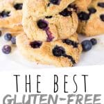 PINTEREST IMAGE with words "The Best Gluten-Free Blueberry Scones" The Best Gluten-Free Blueberry Scones piled on a plate with blueberries on the edge