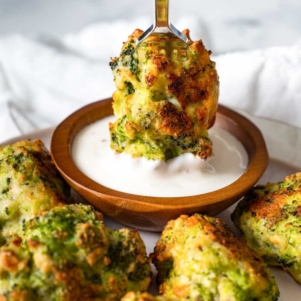 Broccoli Tater Tots on a plate with one being dipped in white sauce