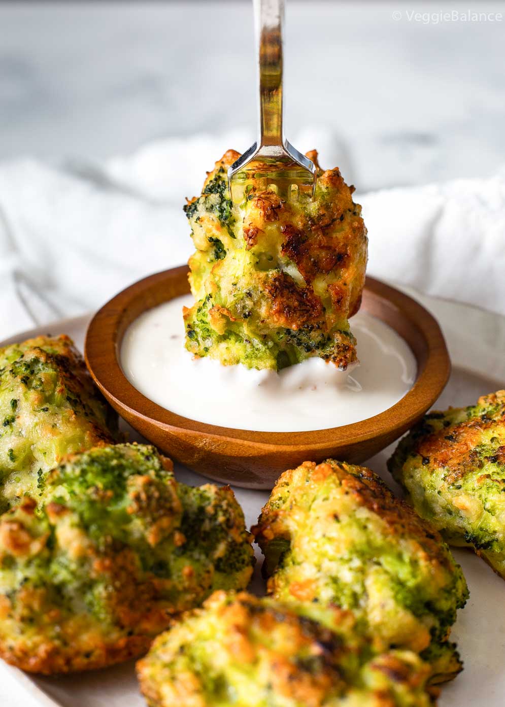 Broccoli Tater Tots on a plate with one being dipped in white sauce