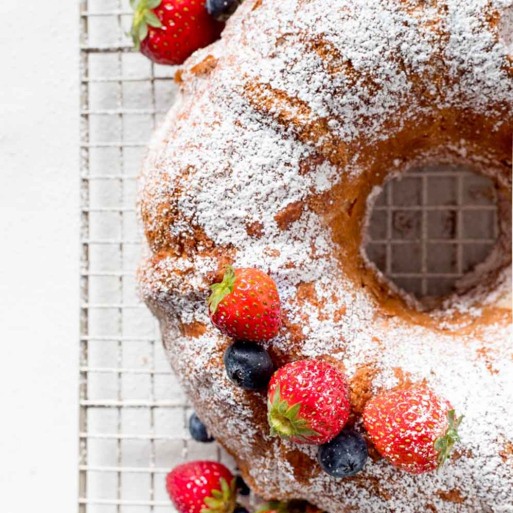 Gluten Free Angel Food Cake with blueberries and strawberries spread around.