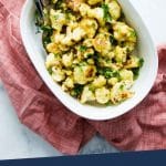 PINTEREST IMAGE with words "Plant Based Cheesy Roasted Cauliflower" Cheesy Roasted Cauliflower in a white bowl on a red tea towel