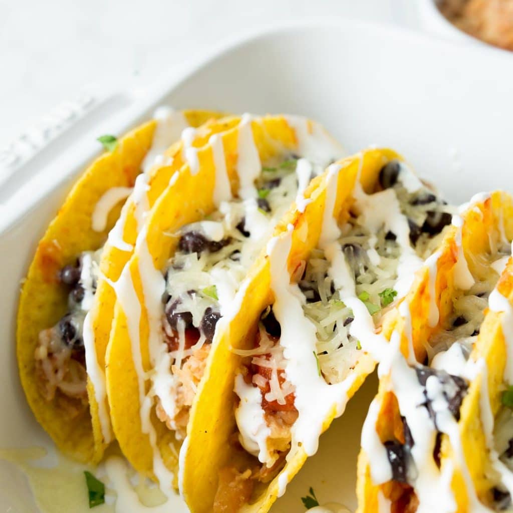 Close-up shot of taco shells stuffed with refried beans, black beans and salsa.