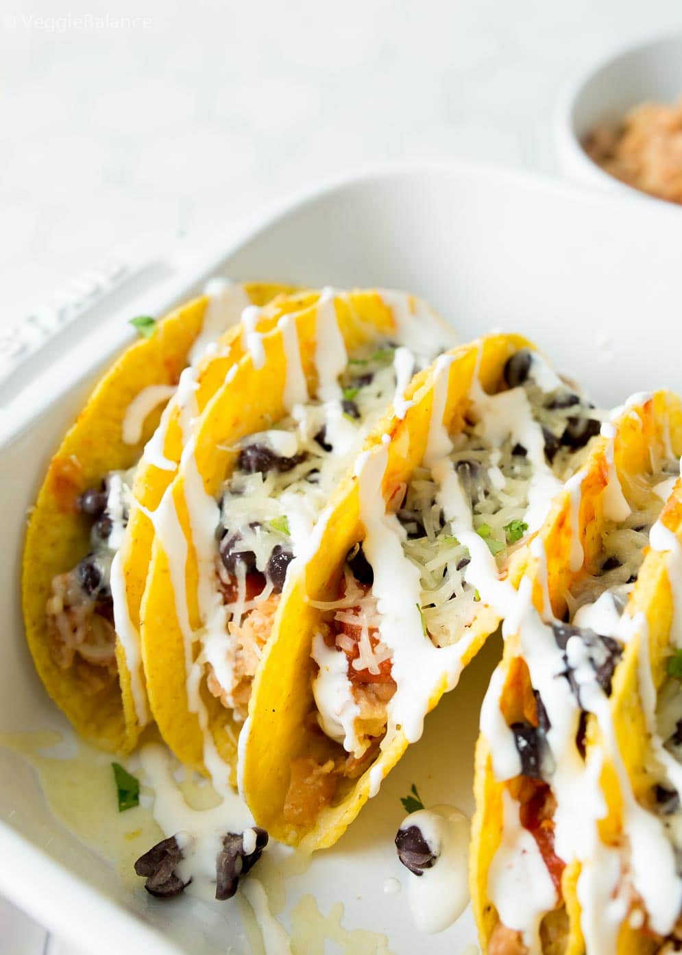 Close-up shot of taco shells stuffed with refried beans, black beans and salsa.