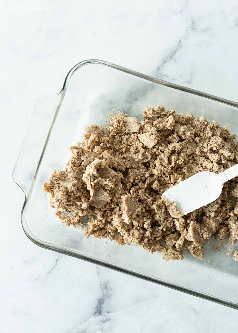 Crust for the Vegan Lemon Bars being pushed into a pan to create the crust