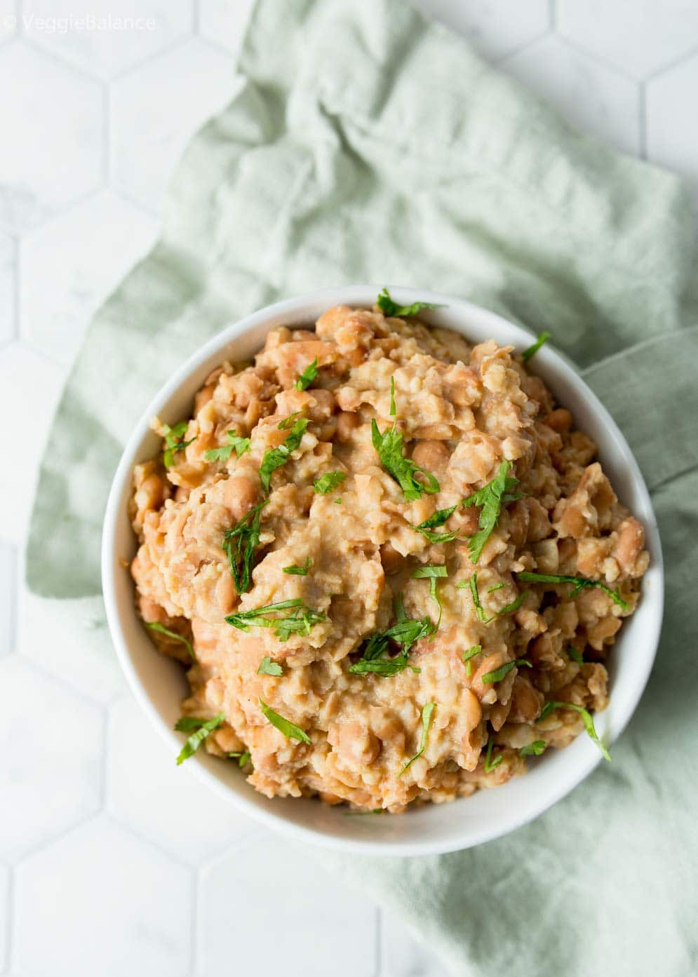 overhead shot of vegetarian refried beans on light green napkin and white table