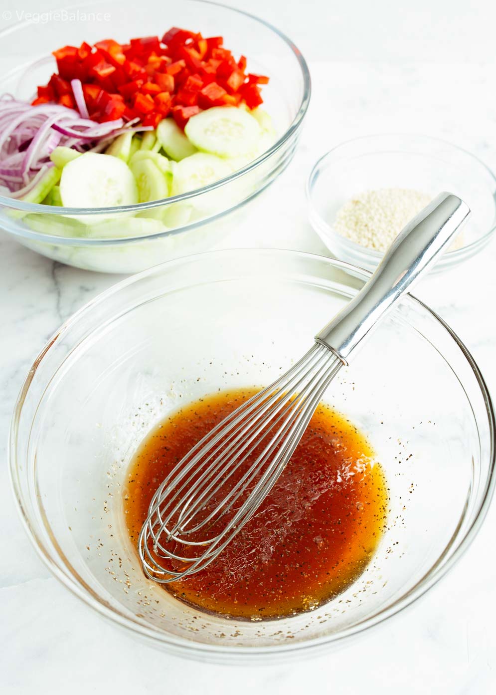 Small bowl filled with asian cucumber salad dressing with whisk sitting in it