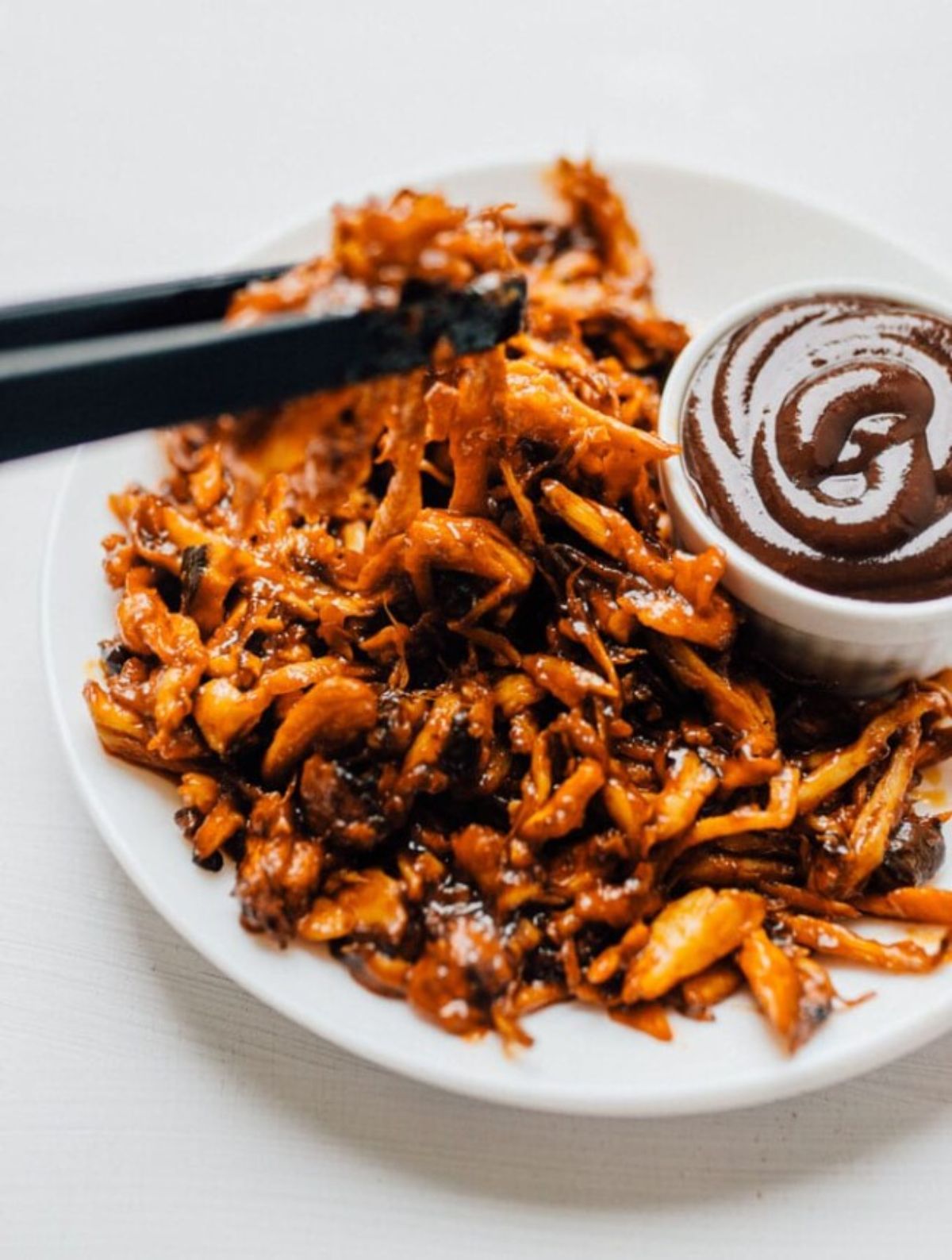 a plate of king oyster mushroom pulled pork with a pot of BBQ dip