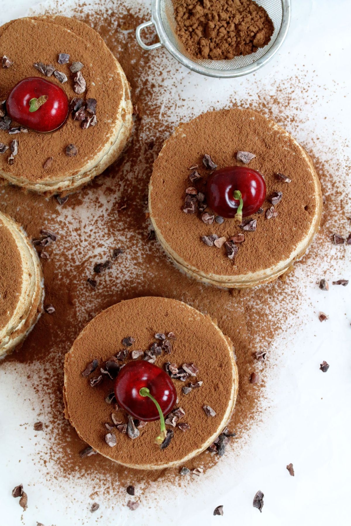 4 mini vegan tofu tiramisu's topped with a cherry and chocolate curls and dusted with cocoa powder