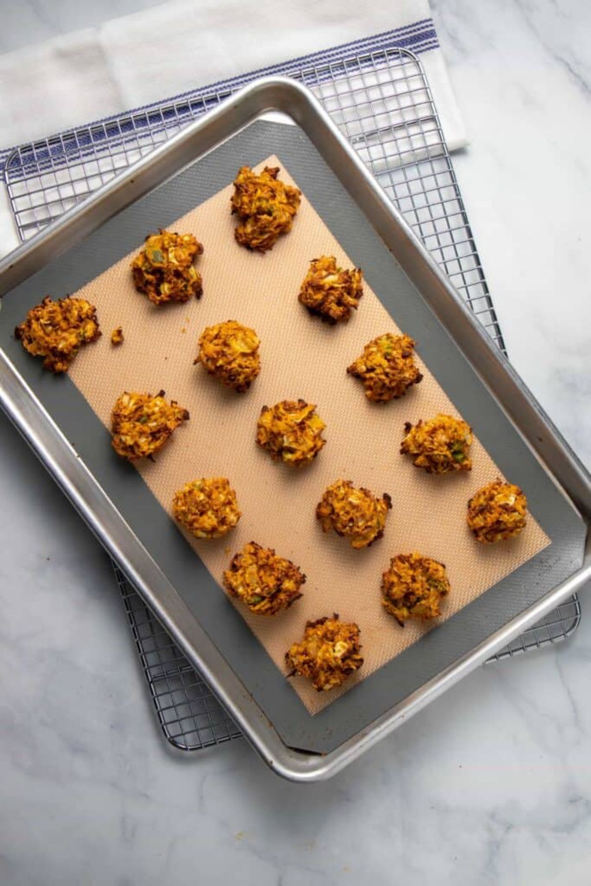 a top view of a baking tray with cabbage fritters laid out on it