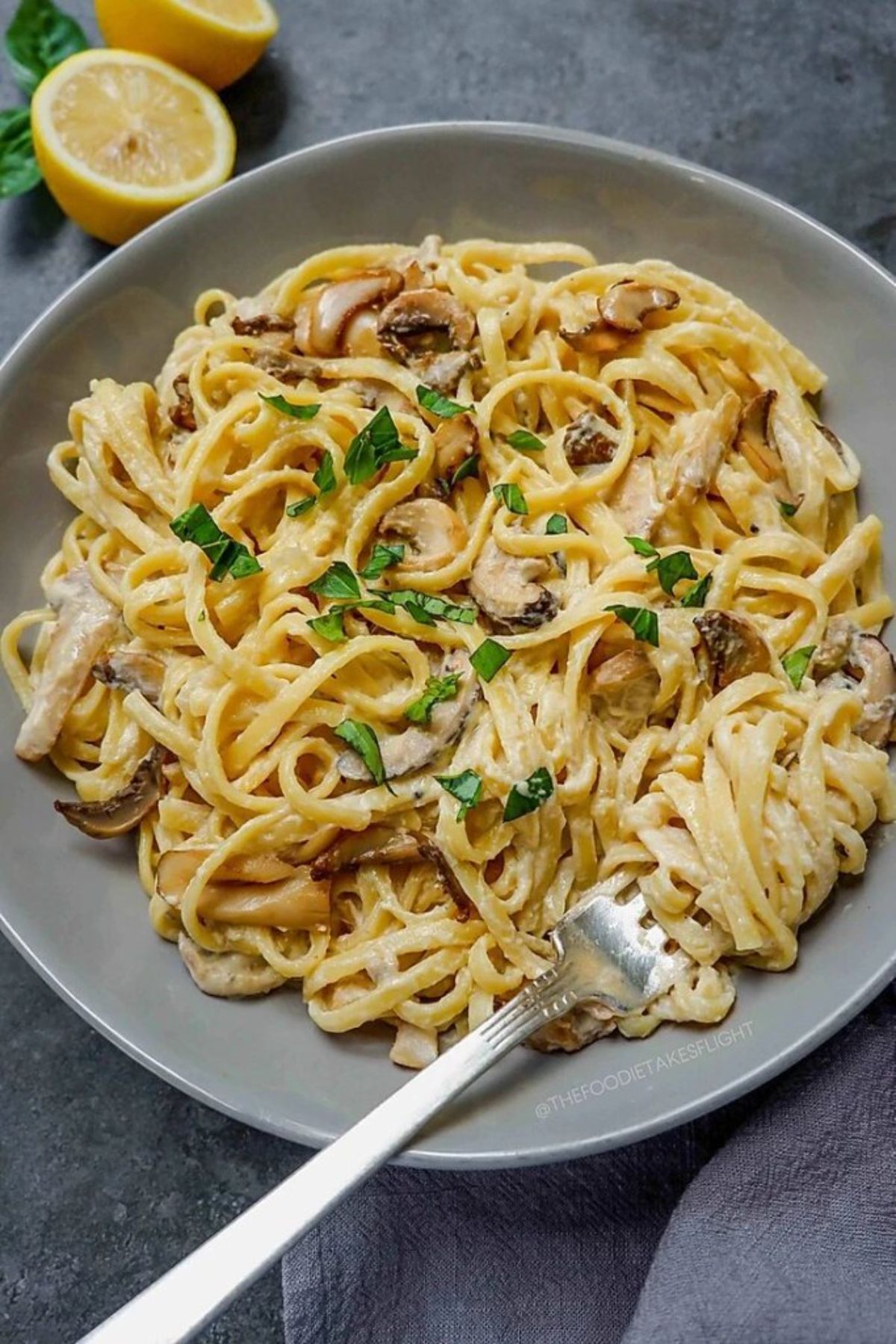 a bowl of creamy lemon and mushroom pasta with a fork in it
