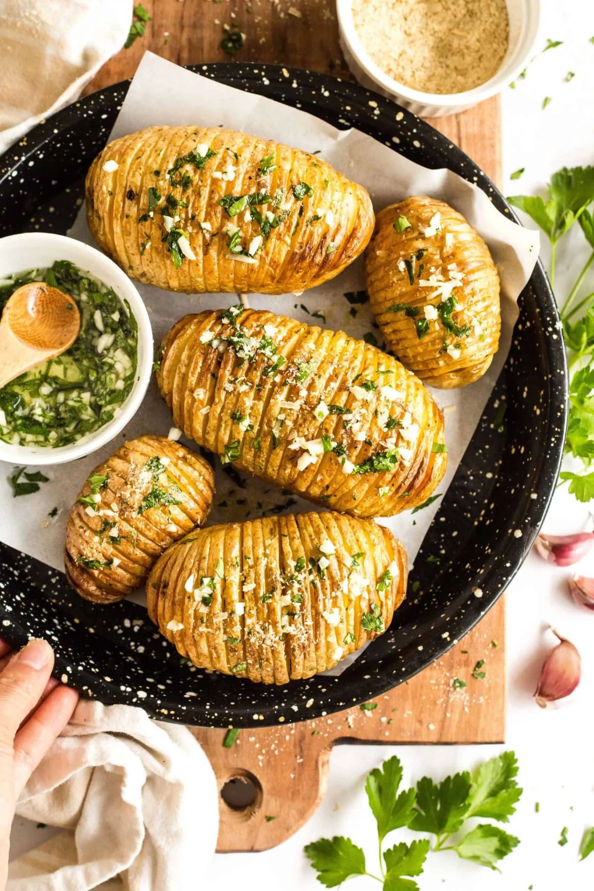 a black plate full of hasselback potatoes scattered with salt and herbs
