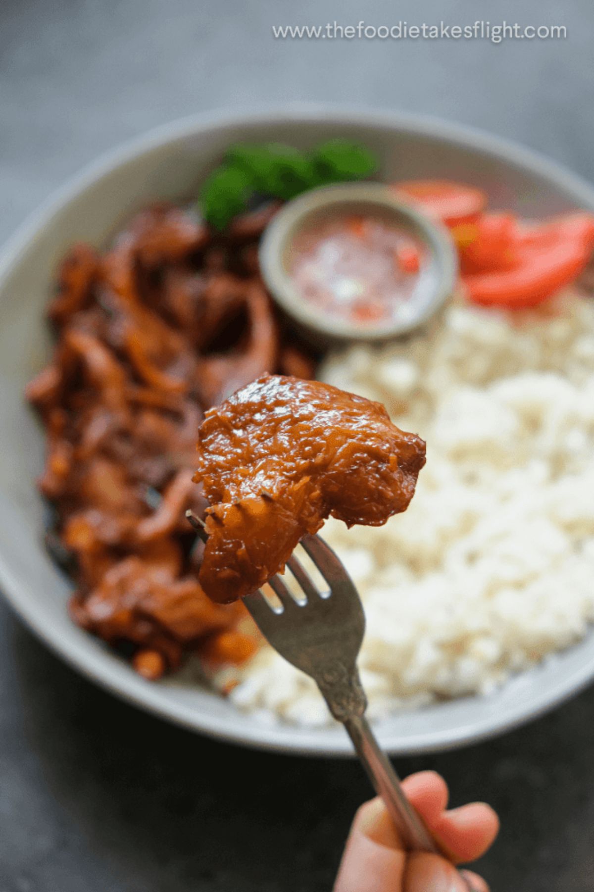 a fork holds a vegan mushroom tocino up to the camera with a blurred bowl of the meal behind