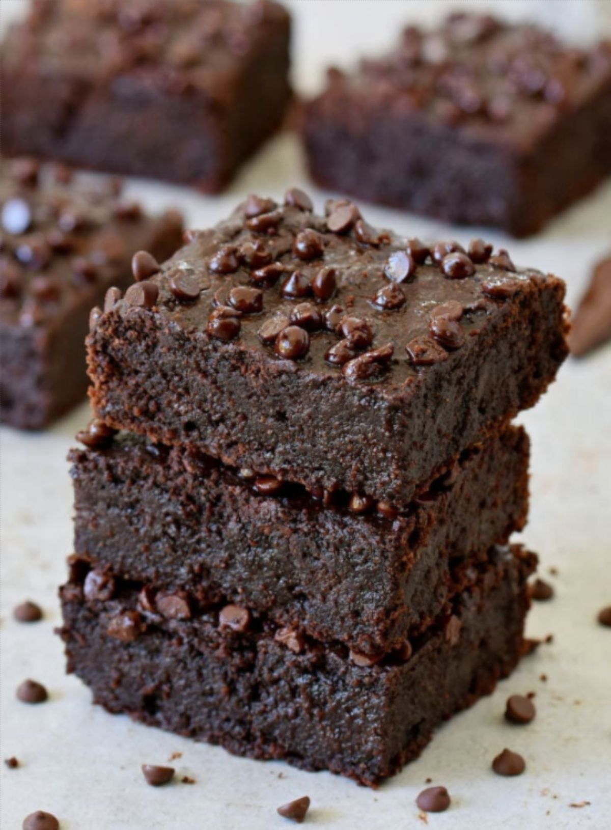 a stack of zucchini brownie bars on a white surface