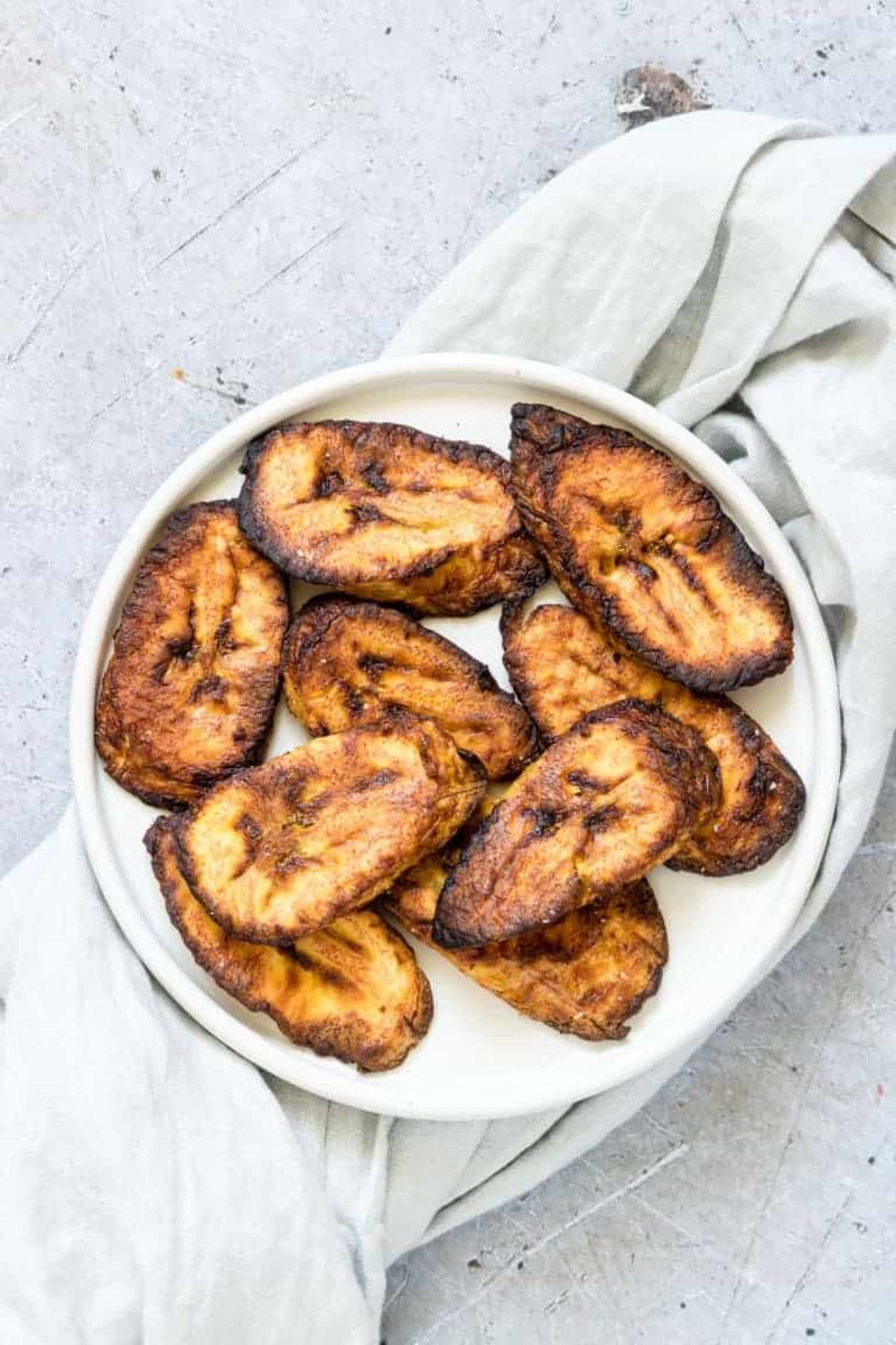 a top view of a white plate full of air fried plantains