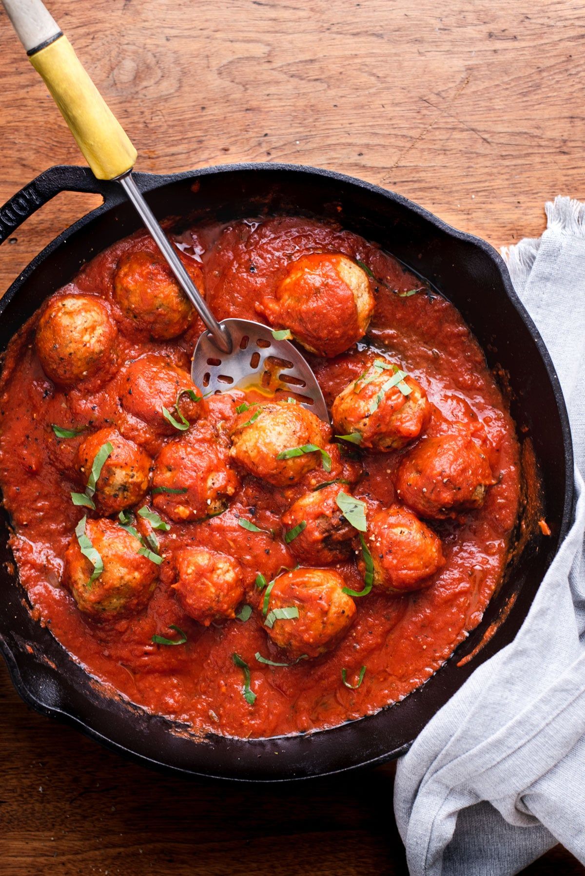 a cast iron dish full of vegan meatballs in tomato sauce