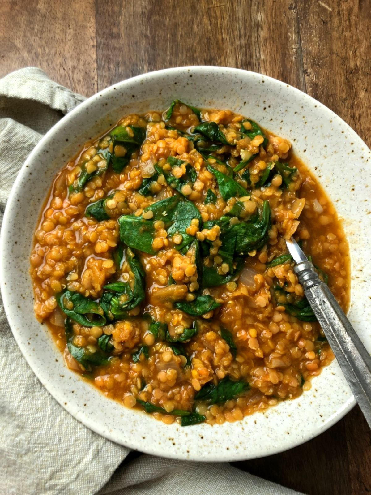 a white bowl of red lentil spinach soup