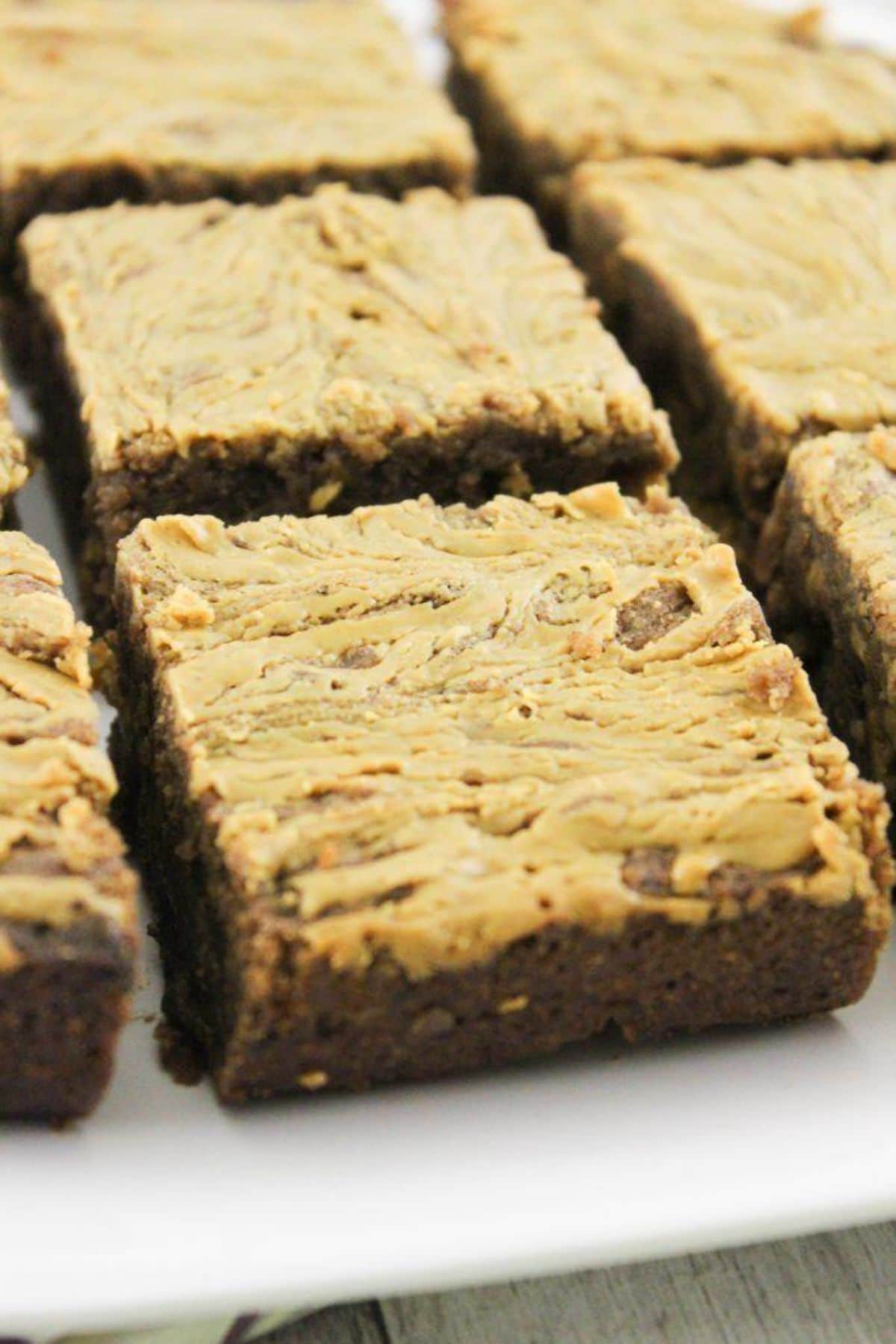squares of vegan peanut butter brownies lay on a white chopping board