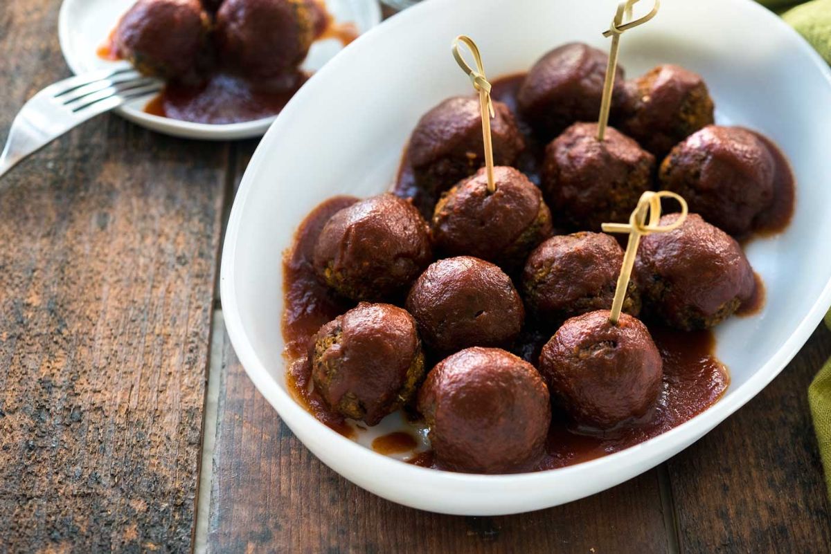 a white bowl full of meatballs in barbecue sauce