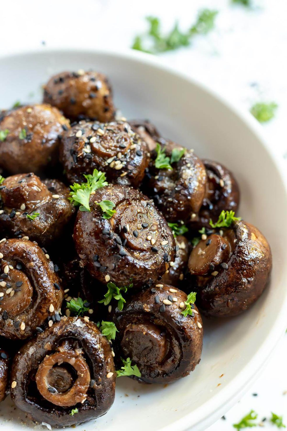 a bowl of ginger soy roasted mushrooms scattered with chopped herbs