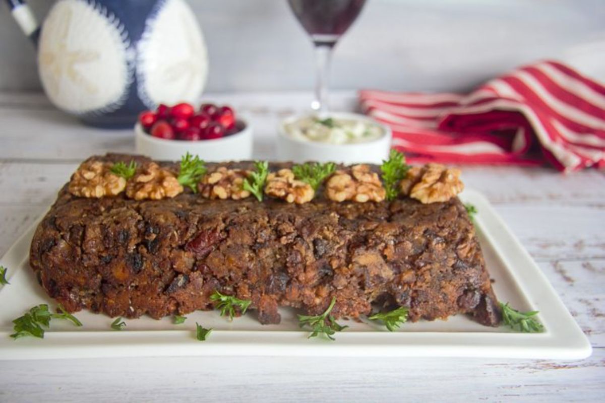 a whole vegan keto mushroom walnut loaf decorated with walnuts and herb sprigs