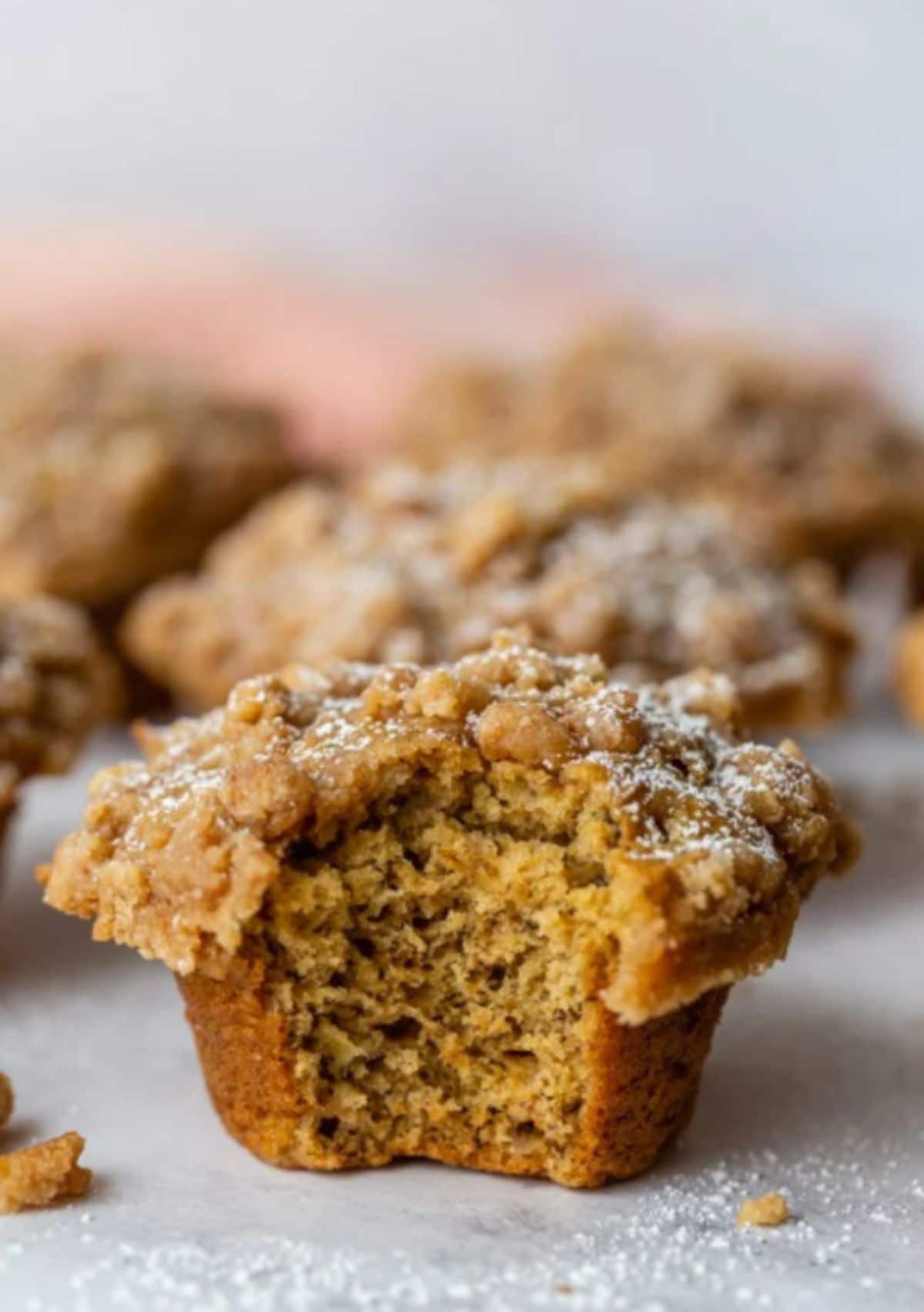 several vegan coffee cake banana muffins, the front muffin has a bite taken out of it