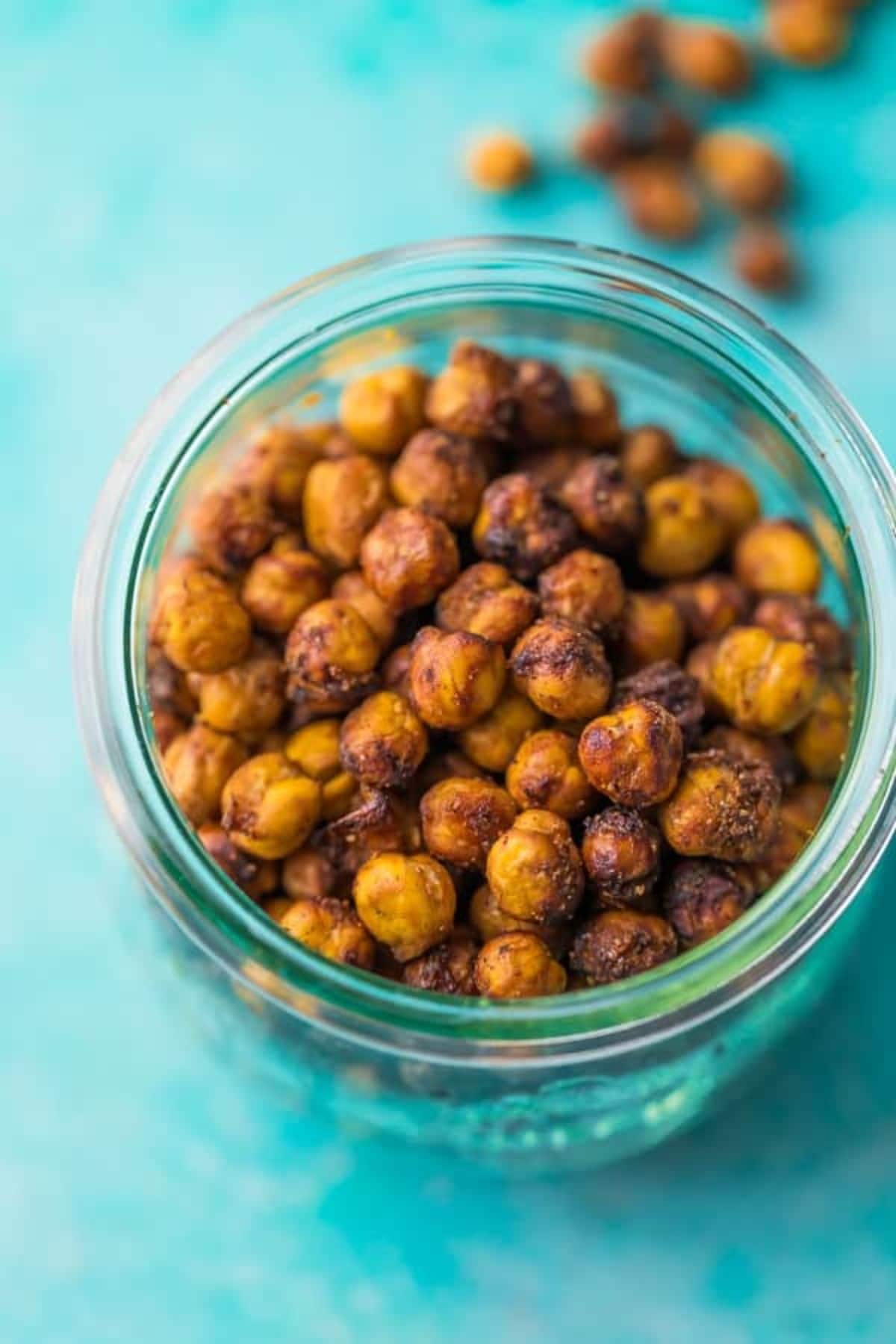 a glass jar full of roasted chickpeas on a blue background