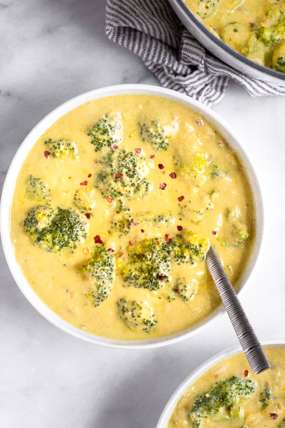 2 white bowls full of broccoli cheese soup