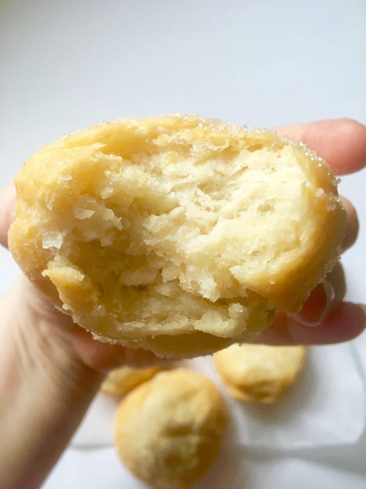 a hand holds a chinese donut toward the camera with a bite taken out of it