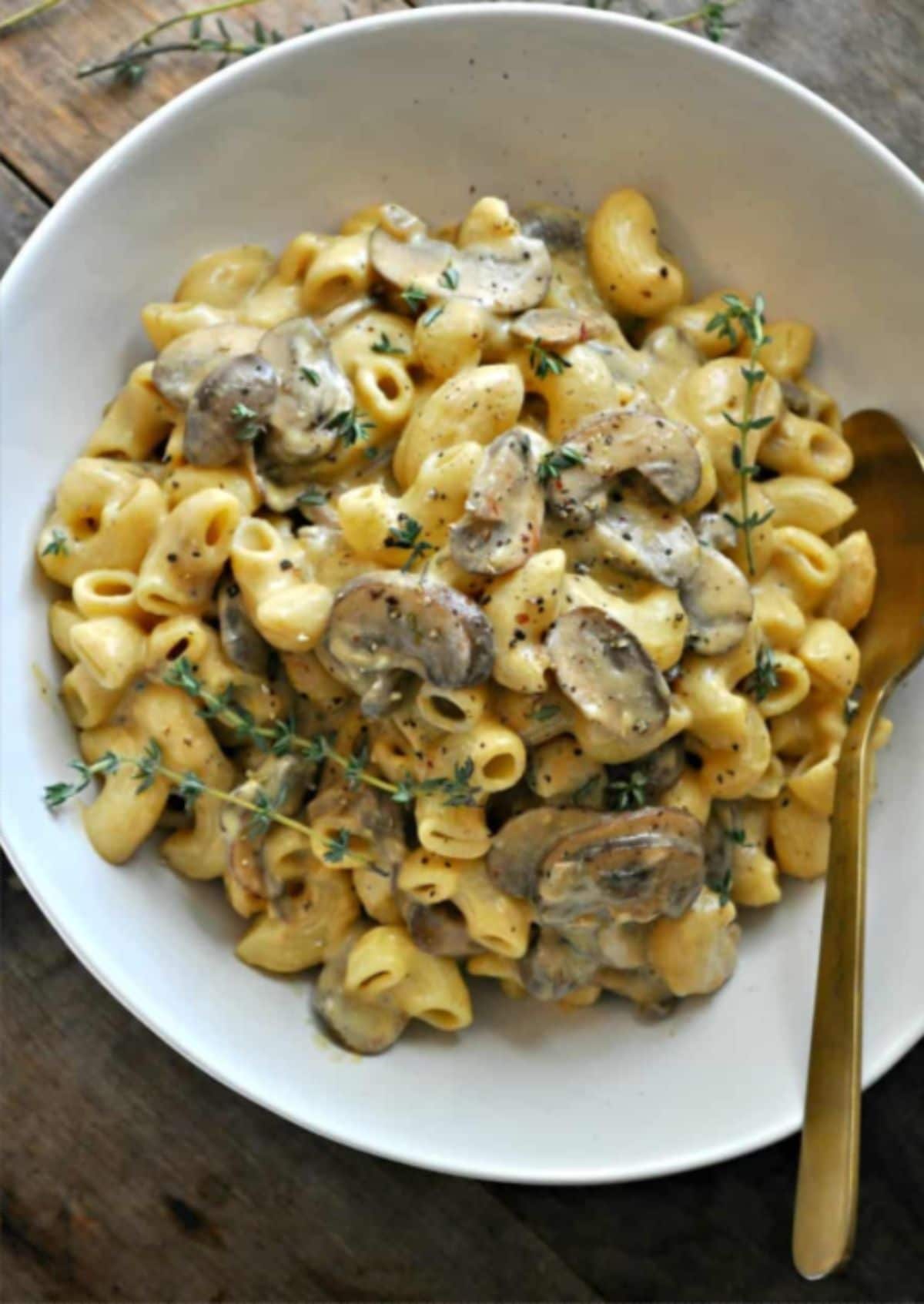 a bowl of mushroom stroganoff mac and cheese topped with fresh thyme