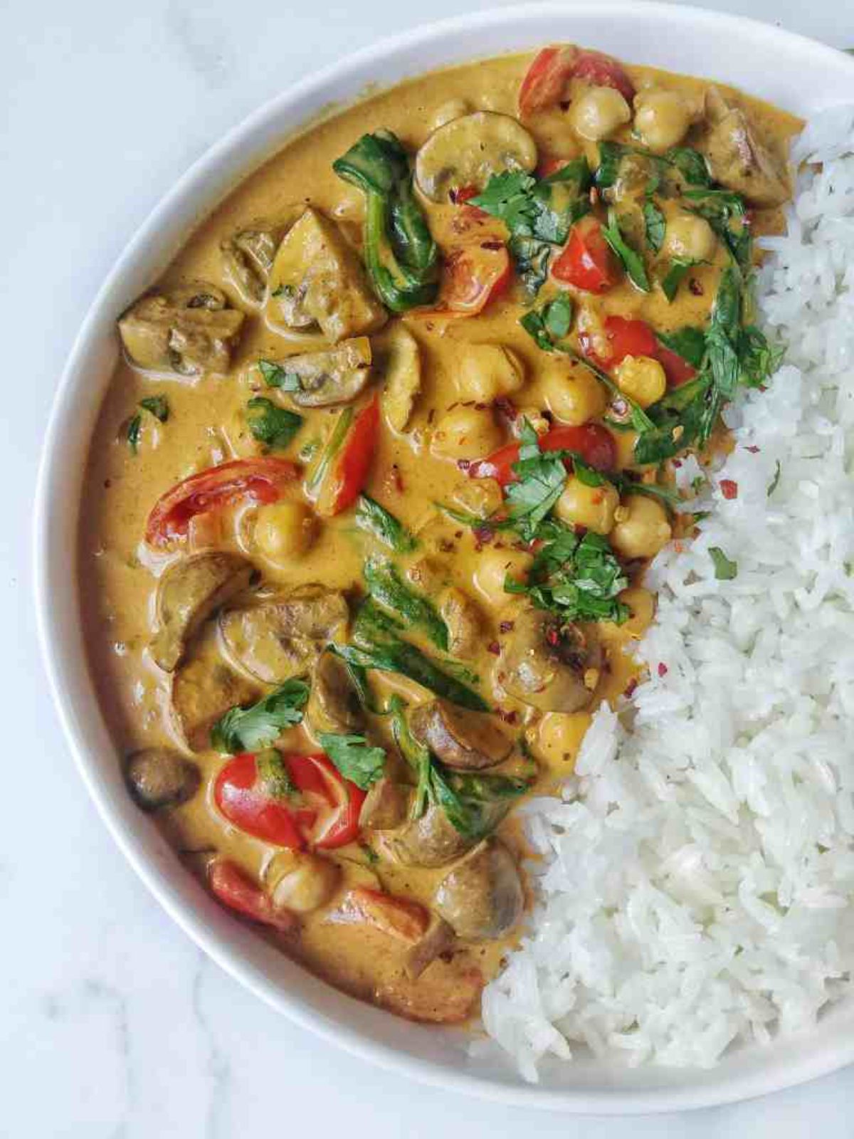 a bowl of vegan mushroom spinach curry with white rice